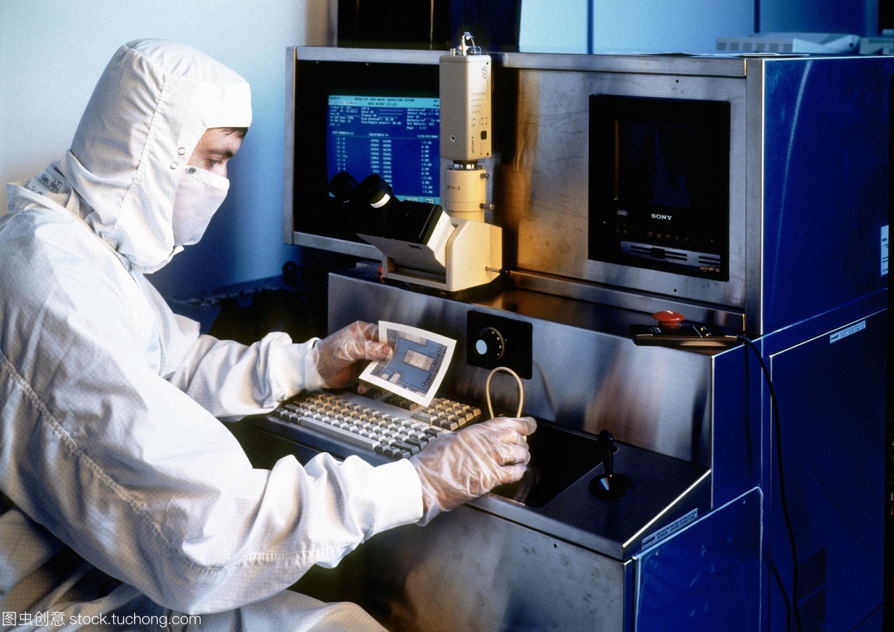 模型發(fā)布。硅晶片檢查。一名技術(shù)人員拿著一張硅片的部分照片,同時對其微電路進行檢查。他坐在顯微鏡下觀察晶圓的放大。這是一個&ldquo;干凈的房間&rdquo;,技術(shù)人員穿著一套身衣,兜帽和面罩。在所有過程涉及人工微電路的制作和測試技術(shù)人員穿防護服和手套空氣潔凈室的過濾。即使是最小的塵埃微粒也可能破壞其中的一個微電路。